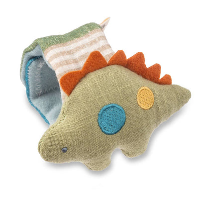 A colorful Itzy Bitzy Wrist Rattle: Dino with blue, orange, and yellow circular patches, resting on a striped natural cotton fabric. The toy is isolated on a white background.