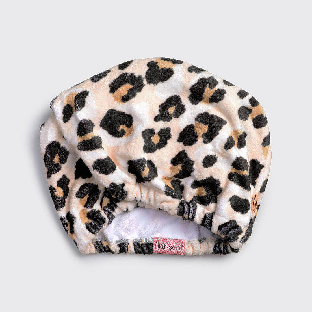 Leopard print microfiber hair towel with elastic opening and pink "kitsch" tag. Reduces frizz, dries fast. Available in one size.
