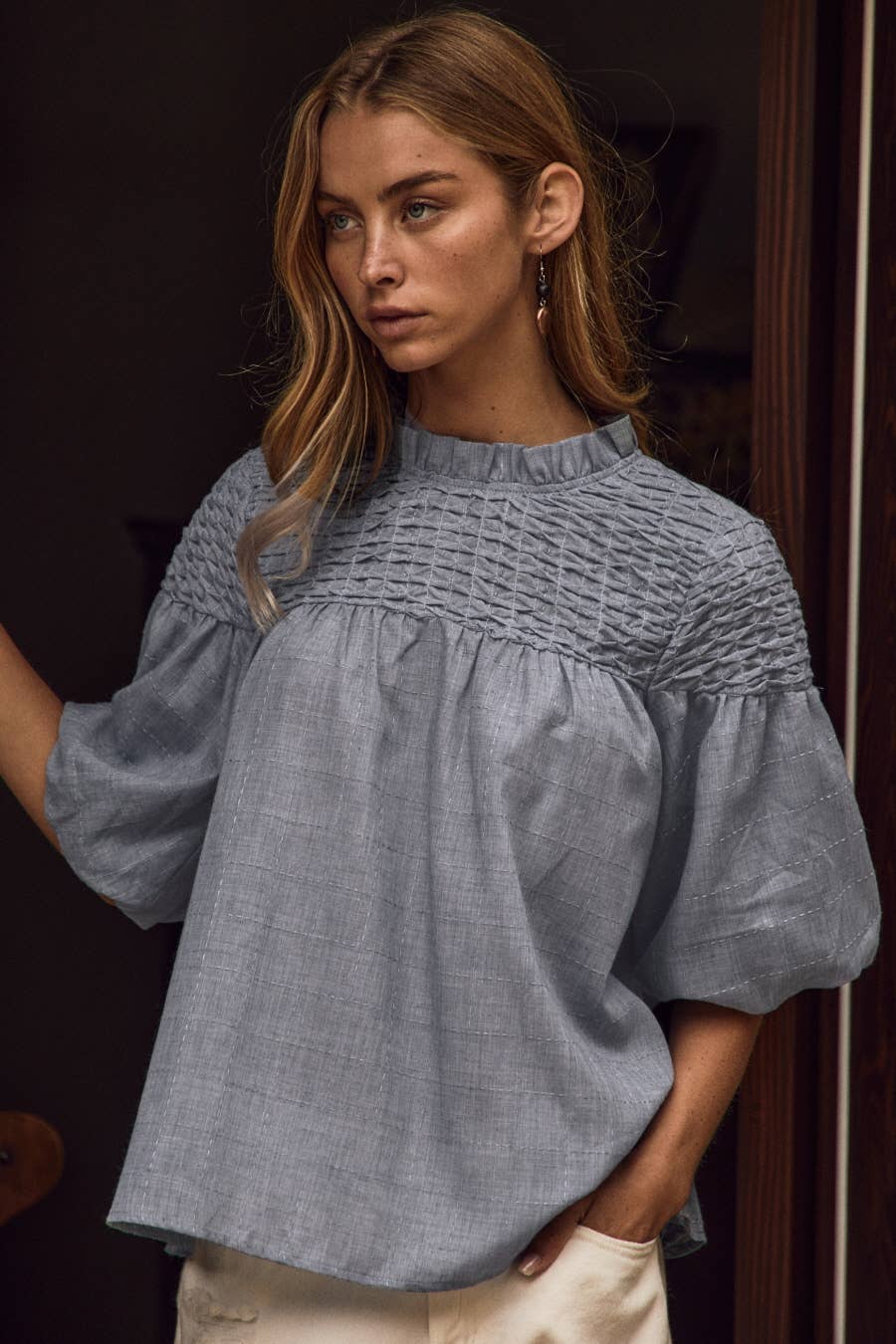 The Bubble Sleeve Blouse in blue features a loose fit, textured fabric, bubble sleeves, and a smocked mock neckline; available in sizes S–XL.