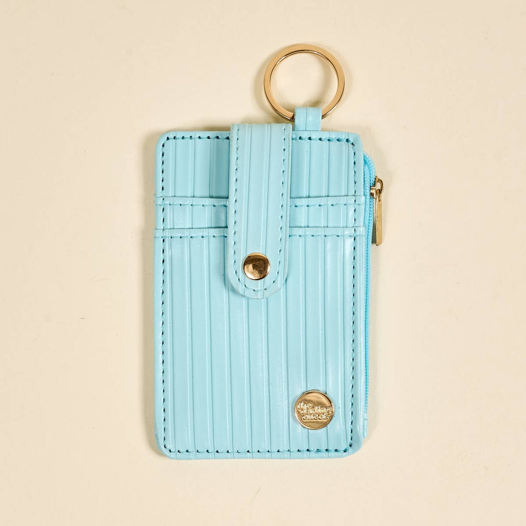 The Ripple Ridge Keychain Wallet–Blue: light blue stripes, gold keyring, snap closure, front pocket, zip coin holder, small gold emblem. Sizes: S/M/L.