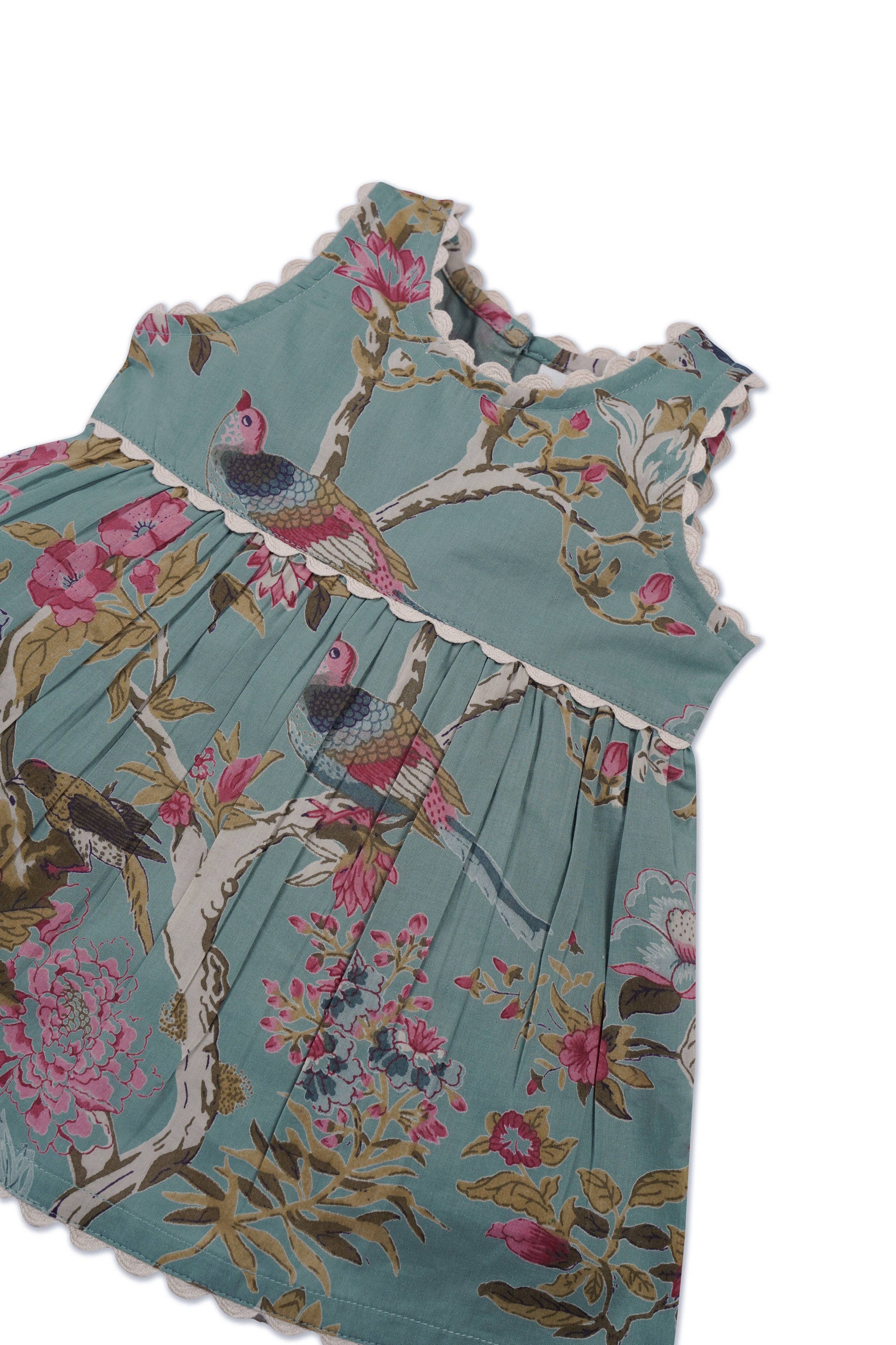 Sleeveless infant dress in sage with scalloped edges, floral and bird prints. Sizes: NB-24M.