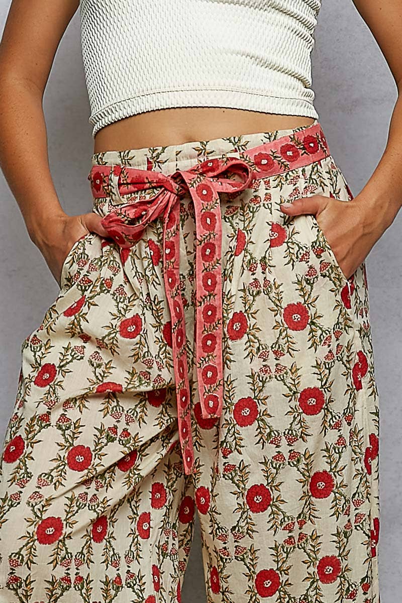 Cream straight fit floral pants with red motif, matching belt. Available in sizes XS–XL.