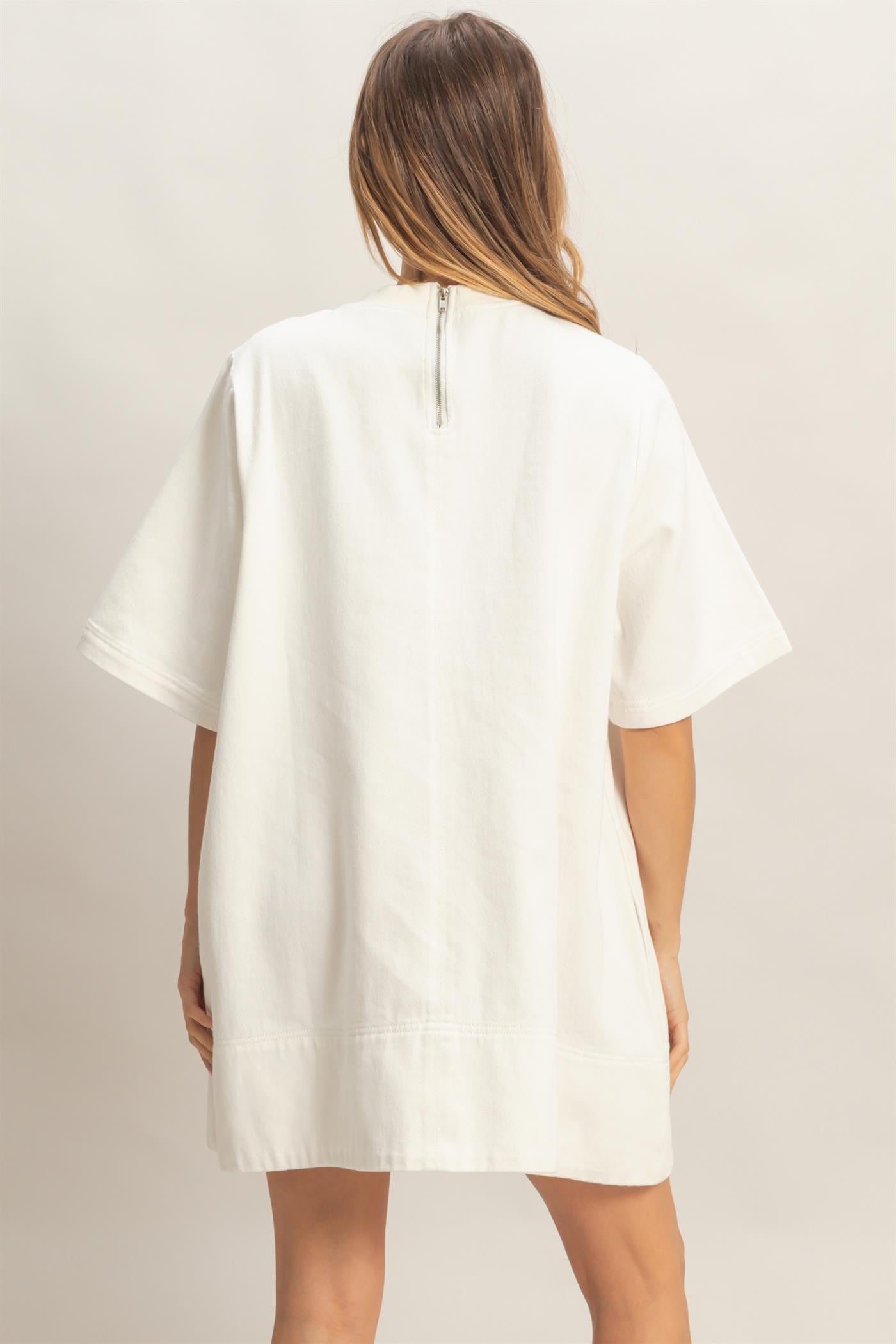 Loose-fitting white crew neck denim tunic with back zipper. Available in sizes XS–XL.