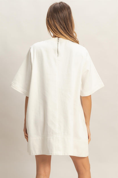 Loose-fitting white crew neck denim tunic with back zipper. Available in sizes XS–XL.
