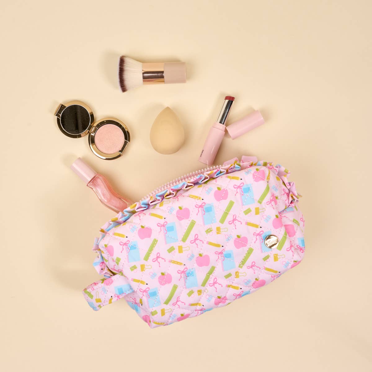 The Essentials Quilted Cosmetic Pouch features bow, perfume, and lipstick patterns with a wipeable lining. Sizes: S, M, L.