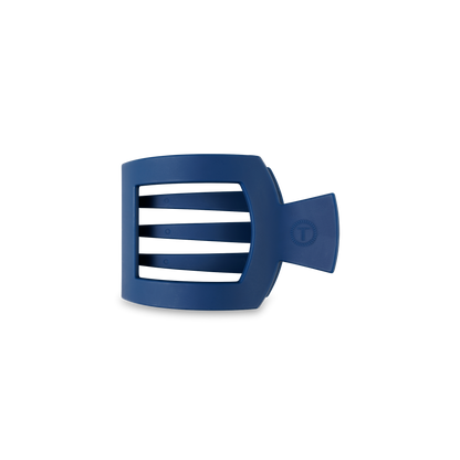 A blue, square hair clip with a strong grip, featuring three horizontal bars and a side handle. Prominent logo and text on the front. Available in small, medium, and large sizes.