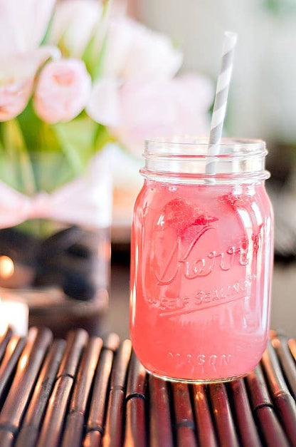 Mason jar of pink lemonade with ice and striped straw; available in 12oz, 16oz, and 24oz sizes.