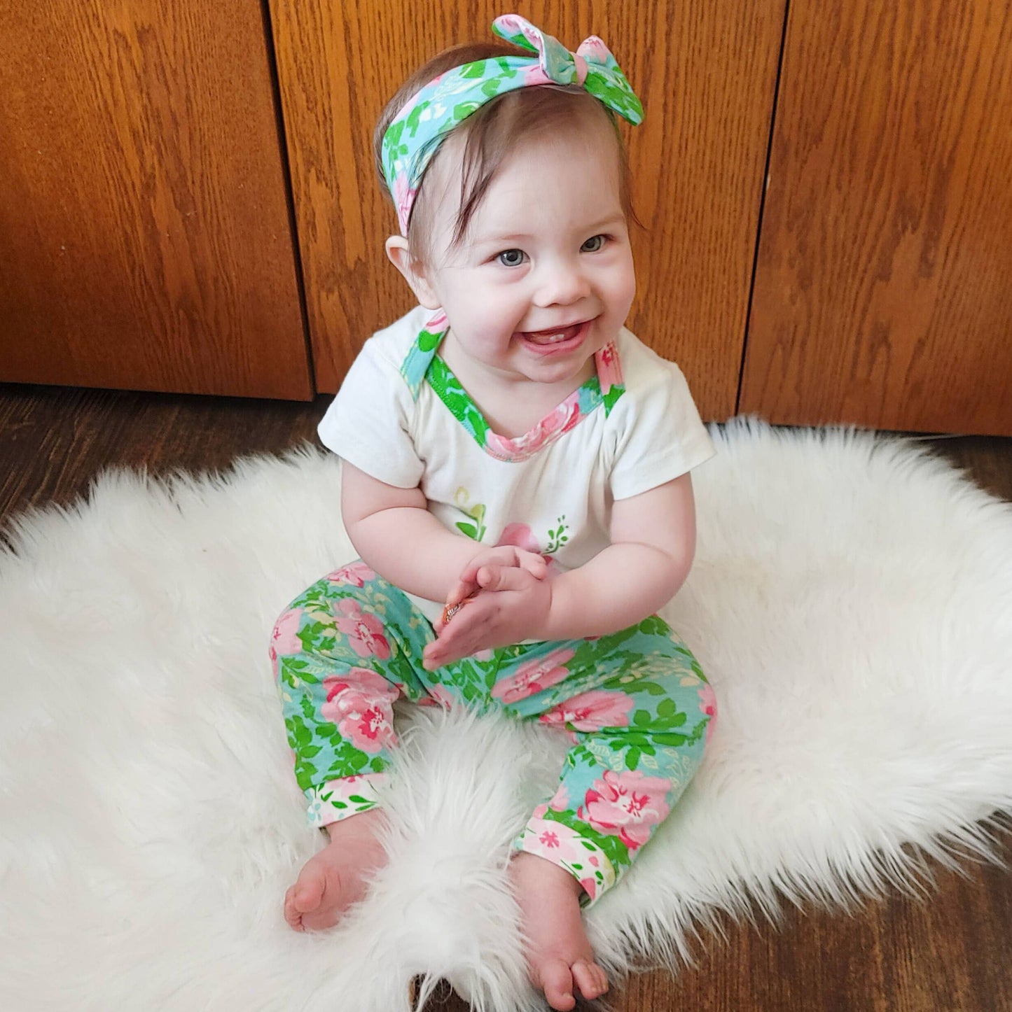 Baby modeling the whole set sitting on the white fur rug clapping her hands.