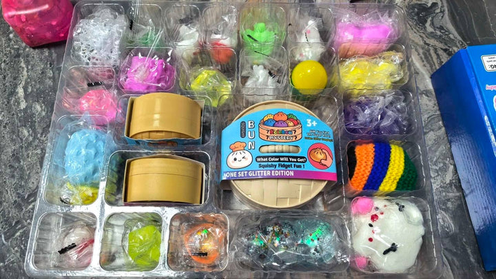 Squishy Mystery Calendar Countdown Days plastic advent calendar tray with mystery squishy toys and a central circular package featuring a cartoon dumpling illustration.