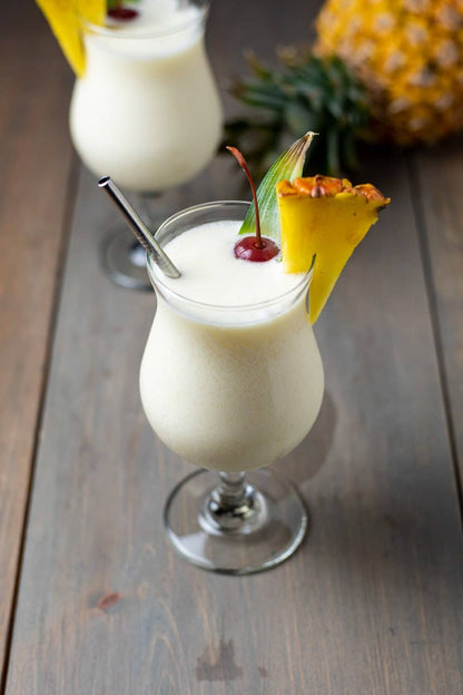 Creamy piña colada in curved glass using Wine & Cocktail Slush Mix Bags, available in 8oz and 16oz sizes, with metal straw.
