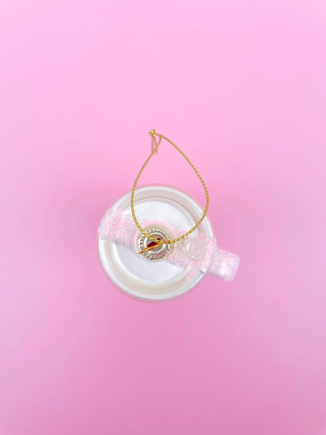 Pink glittered tumbler Christmas ornament with a white base, pink glitter band, and gold hanging string.