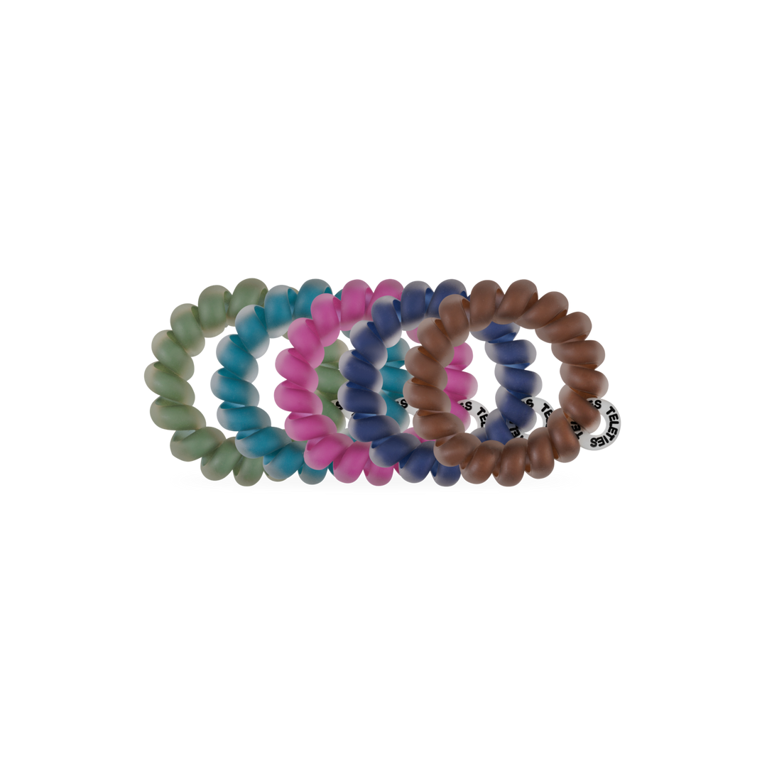Sweater Swatches Tiny Hair Ties come in green, pink, blue, and brown. Each is circular, translucent, and has a small black and white brand tag. Available in one size.