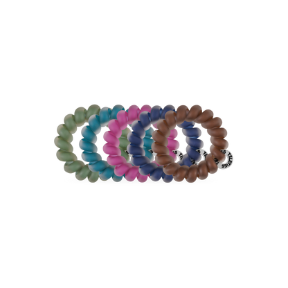 Sweater Swatches Tiny Hair Ties come in green, pink, blue, and brown. Each is circular, translucent, and has a small black and white brand tag. Available in one size.