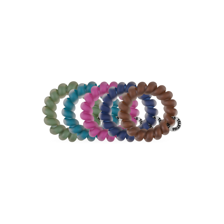 Sweater Swatches Tiny Hair Ties come in green, pink, blue, and brown. Each is circular, translucent, and has a small black and white brand tag. Available in one size.
