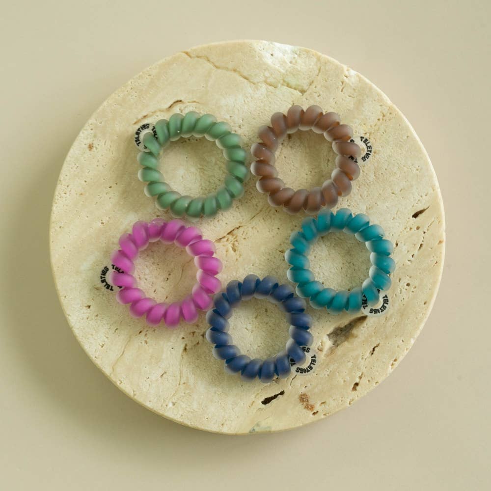 Five Sweater Swatches Tiny Hair Ties in green, brown, teal, blue, and purple. Available in one size for kids or fine hair.