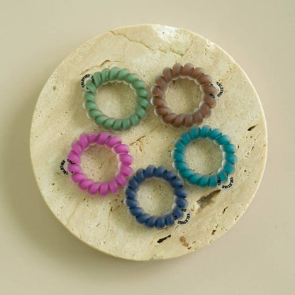 Five Sweater Swatches Tiny Hair Ties in green, brown, teal, blue, and purple. Available in one size for kids or fine hair.