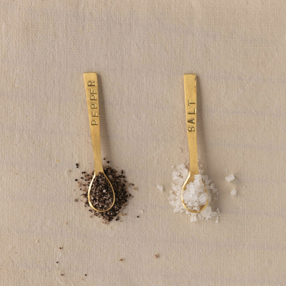Set of two 3-1/4" metal spoons with a brushed brass finish, labeled "Salt" and "Pepper.