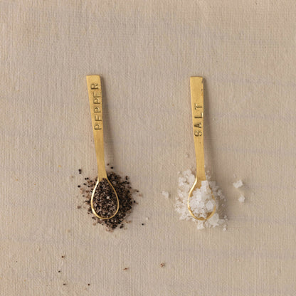Set of two 3-1/4" metal spoons with a brushed brass finish, labeled "Salt" and "Pepper.