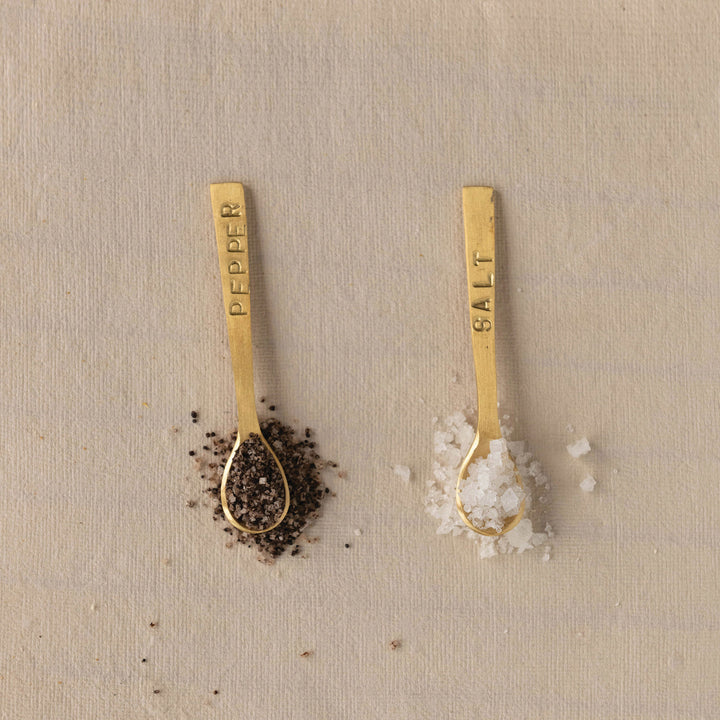 Set of two 3-1/4" metal spoons with a brushed brass finish, labeled "Salt" and "Pepper.
