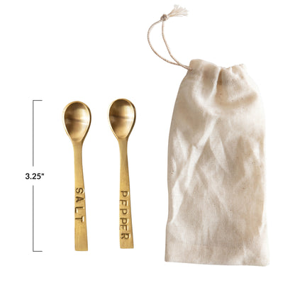 Set of two 3-1/4" metal spoons with brass finish, labeled "SALT" and "PEPPER." Includes cream-colored drawstring bag.