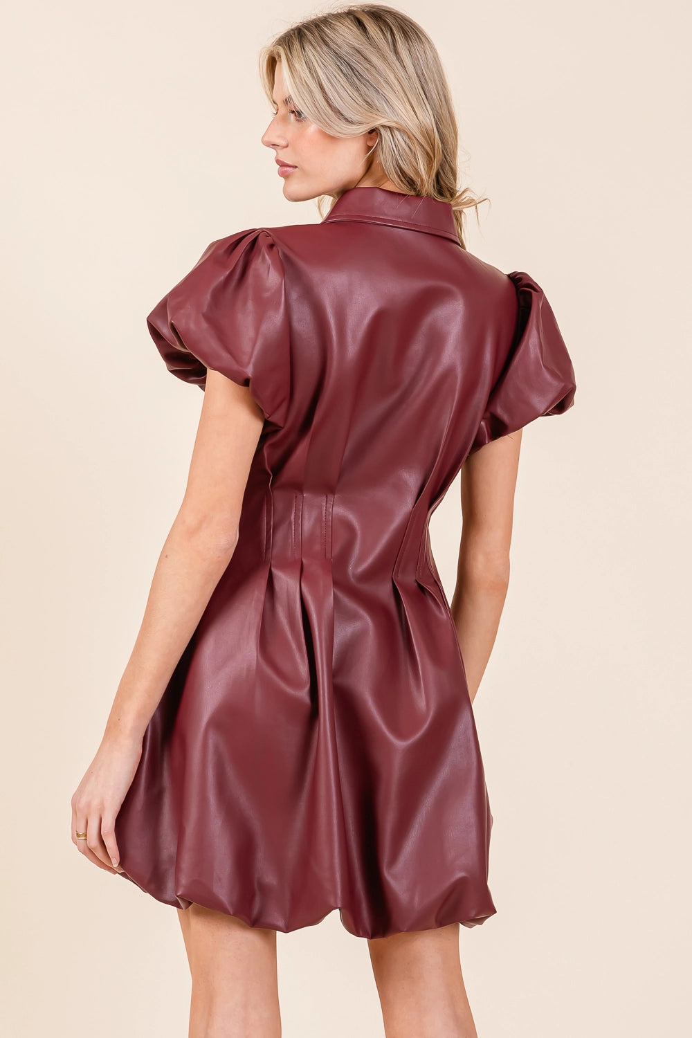 The Faux Leather Puff Sleeve Shirt Mini Dress in a wine color features elegant back details and puff sleeves. Available sizes: XS, S, M, L.