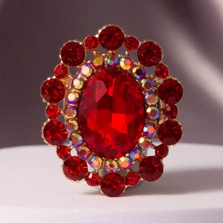 Gold stretch ring with large oval red crystal, surrounded by smaller red and iridescent crystals. Sizes: adjustable.