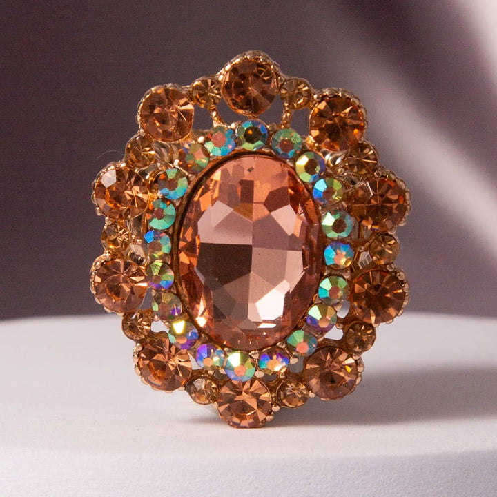 Oval Crystal Sunburst Double Halo Stretch Ring with amber, orange, and iridescent stones on gold-tone band. Sizes available.