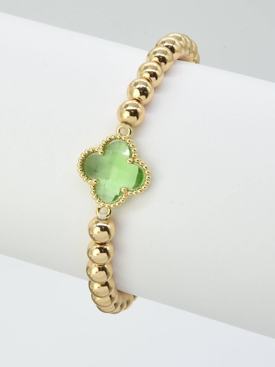 Gold beaded bracelet with green crystal clover charm at center. Sizes available: S, M, L.