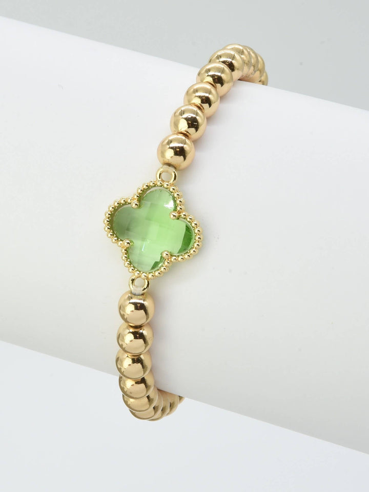 Gold beaded bracelet with green crystal clover charm at center. Sizes available: S, M, L.