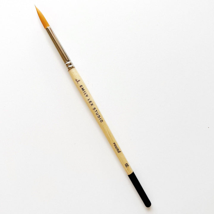 Watercolor paintbrush, size 0, round wooden handle, metal ferrule, fine synthetic bristles, "EMILY EX STUDIO" label.