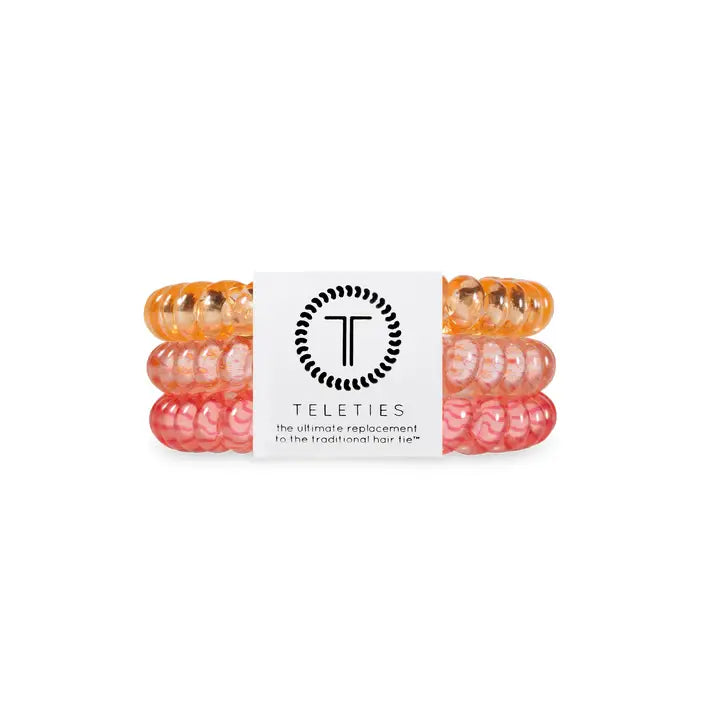 Three TELETIES Hair Ties in orange, coral, and pink with TELETIES logo band; available in small, medium, and large sizes.