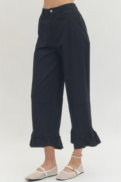 Black straight leg ruffle hem pants with cropped fit; available in sizes XS–XL.