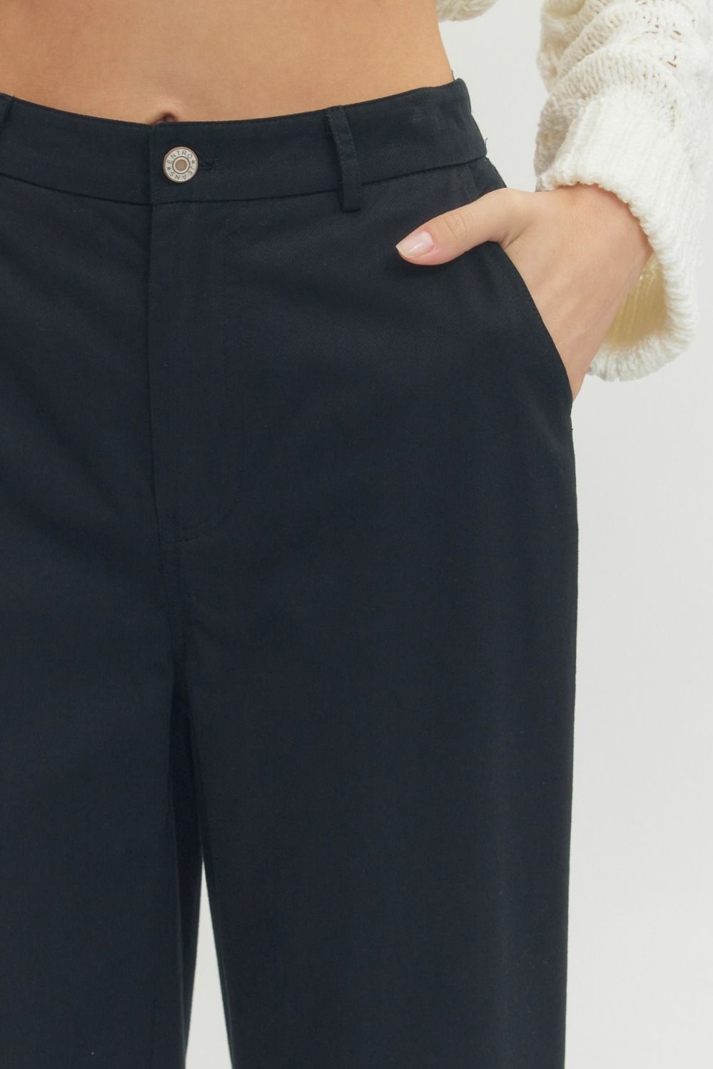 Black Straight Leg Ruffle Hem Pants with visible waistband and button. Available in sizes XS-XL. Cream sweater not included.