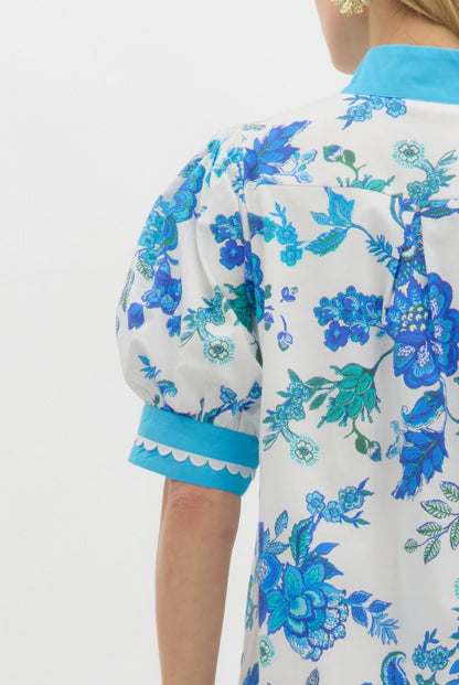 Blue Blossom Caftan Mini Dress with bright blue and teal floral print, puffed short sleeves, turquoise scalloped collar, and A-line silhouette. Available in sizes XS–XL.