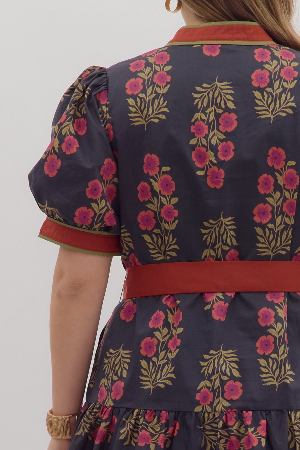 Navy dress with pink flowers, green stems, puff sleeves, ruffle hem, red belt and collar. Sizes: XS-XL.