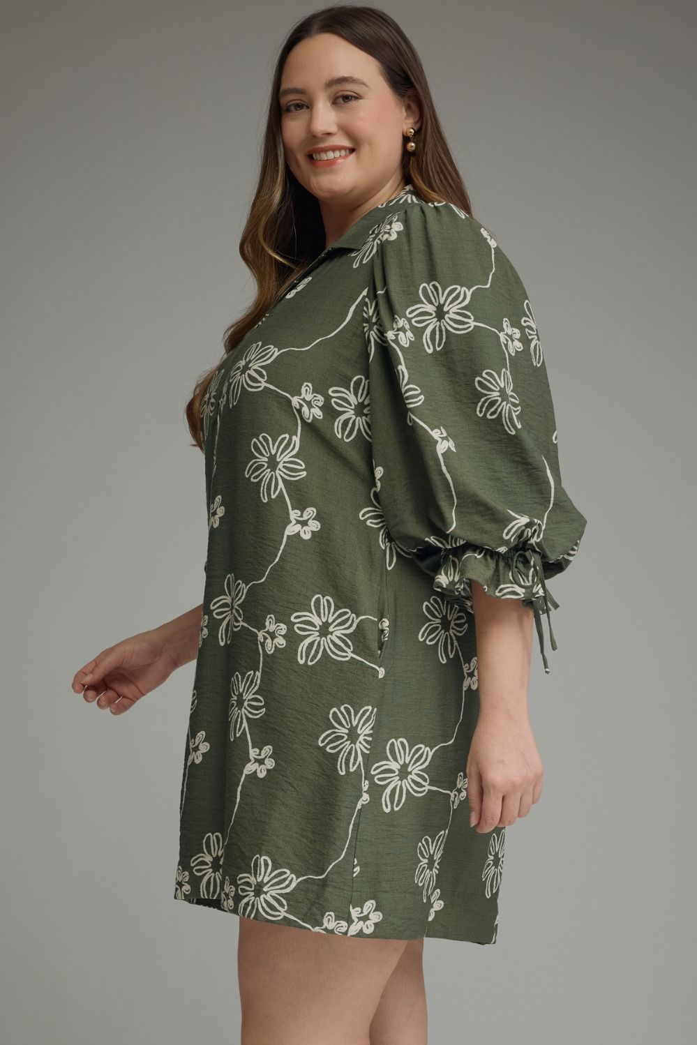 Olive Bloom Tie Waist Dress with white floral patterns and puffy sleeves. Available in sizes XS-XL.