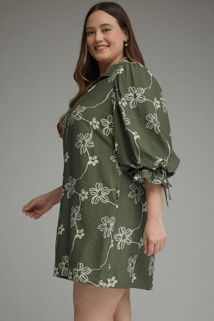 Olive Bloom Tie Waist Dress with white floral patterns and puffy sleeves. Available in sizes XS-XL.