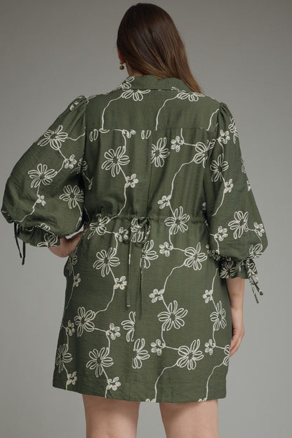 Olive Bloom Tie Waist Dress in olive green with white floral patterns, puffed sleeves, and a tie waist. Available in sizes XS to XL.