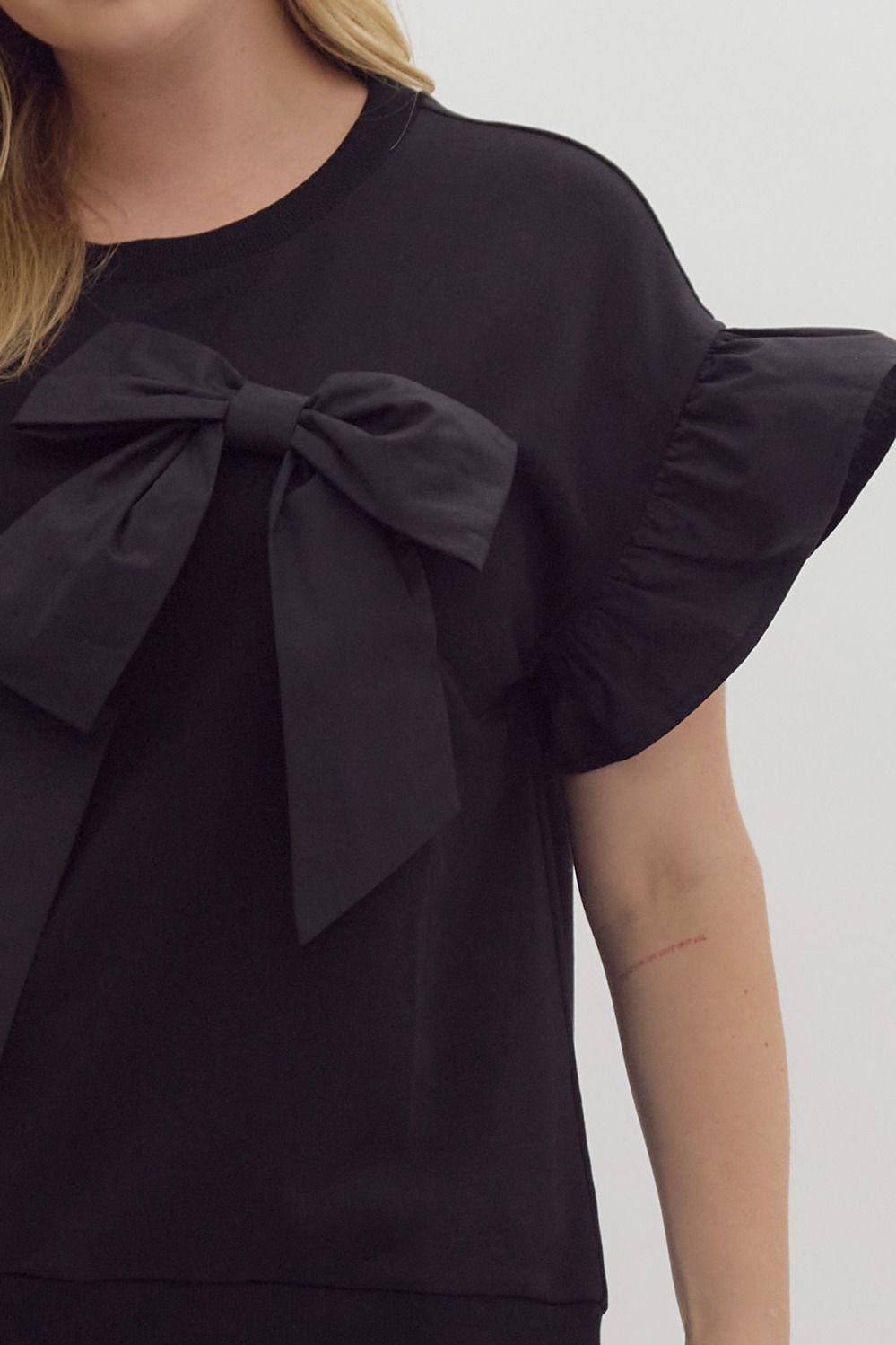 Black Ruffle Sleeve Ribbon Top features elegant ruffle sleeves and a large ribbon bow on the front. Sizes available: S, M, L, XL.