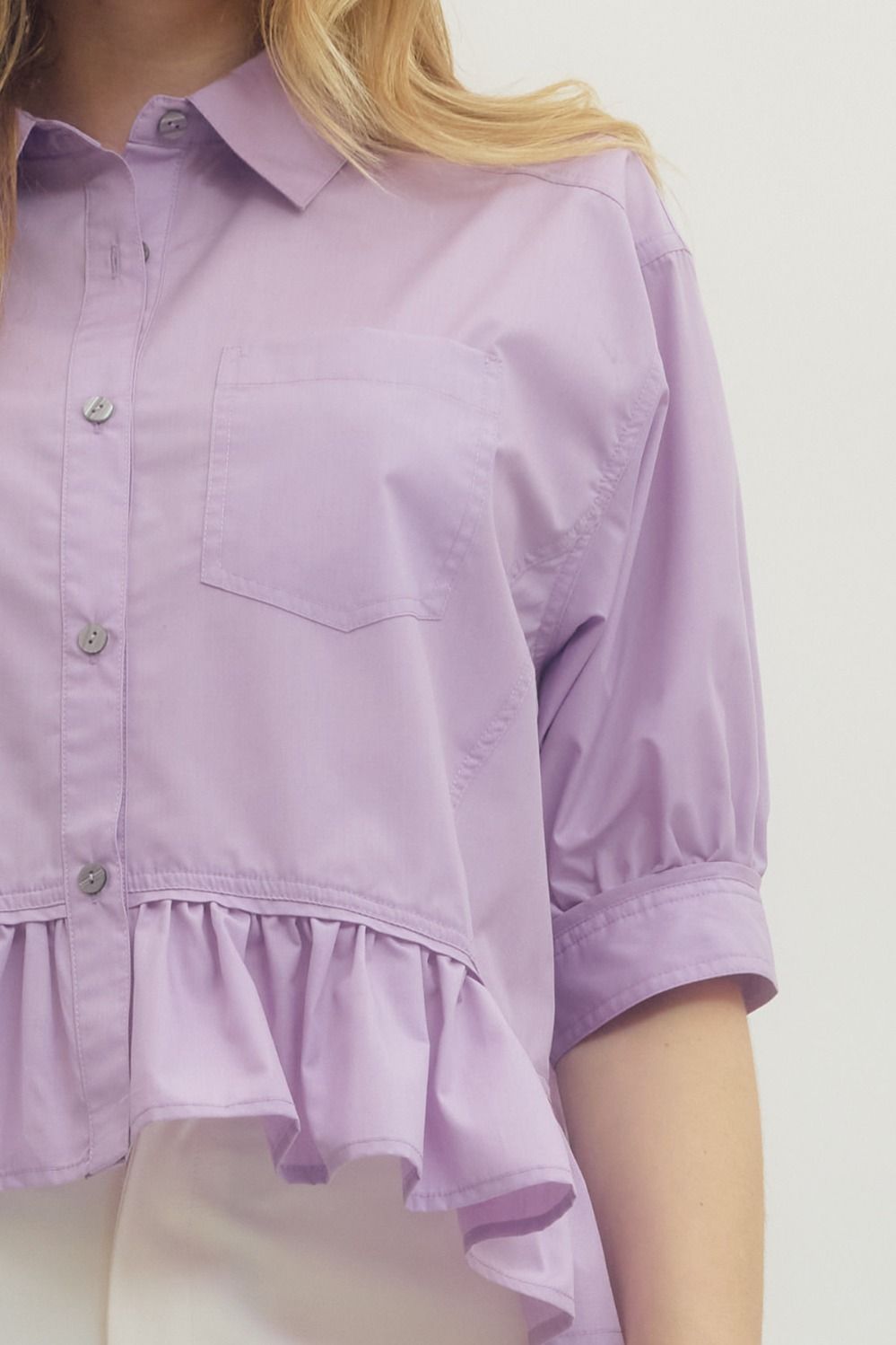 Lavender Ruffle Hem Button-Up Top with short sleeves, chest pocket, and ruffle hem. Available in sizes S-XL.