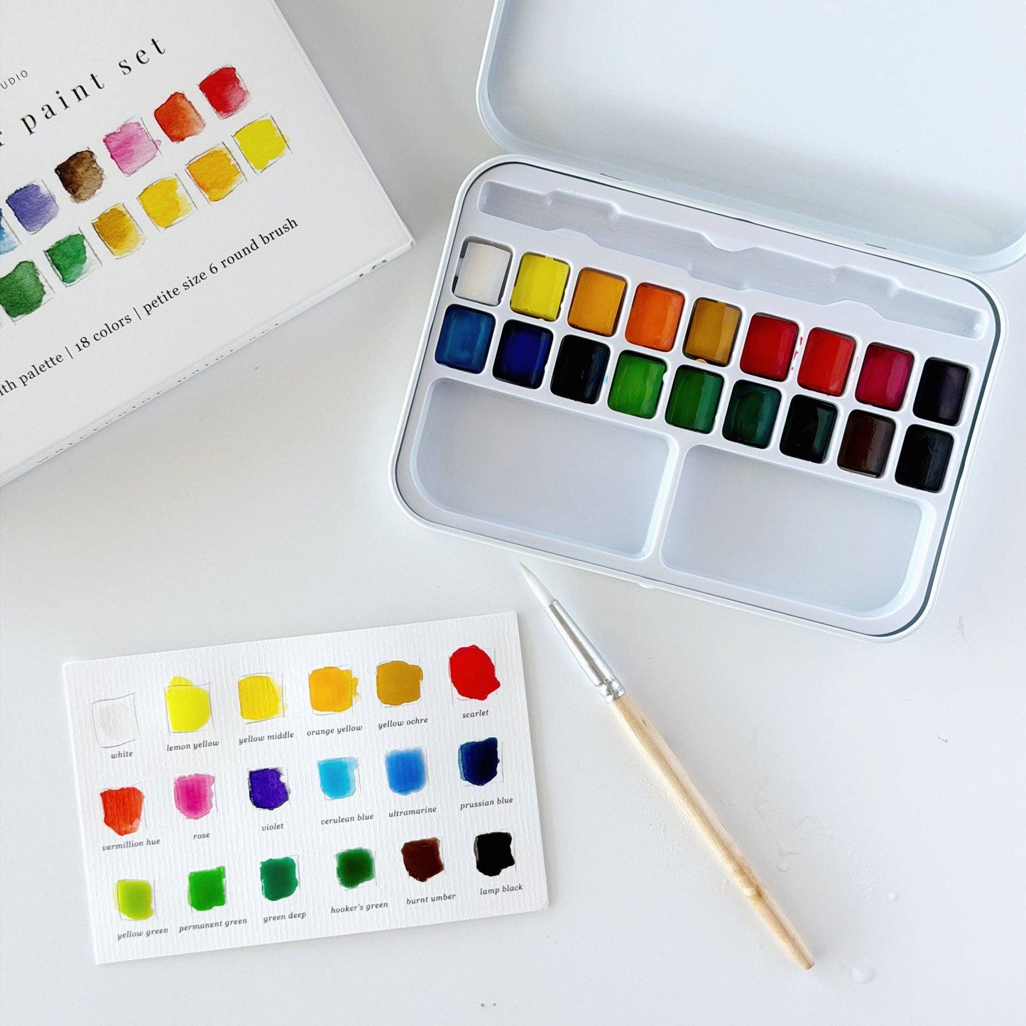 Watercolor paint set with 18 vibrant shades in a sturdy metal tin, includes paintbrush and color chart with swatches and names. Available in 18-color size.