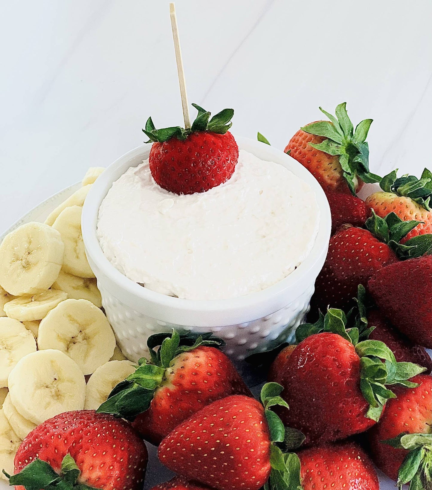 Strawberries N Cream Cheesecake Dip in white bowl, creamy mix topped with whole strawberry. Available in small and large sizes.