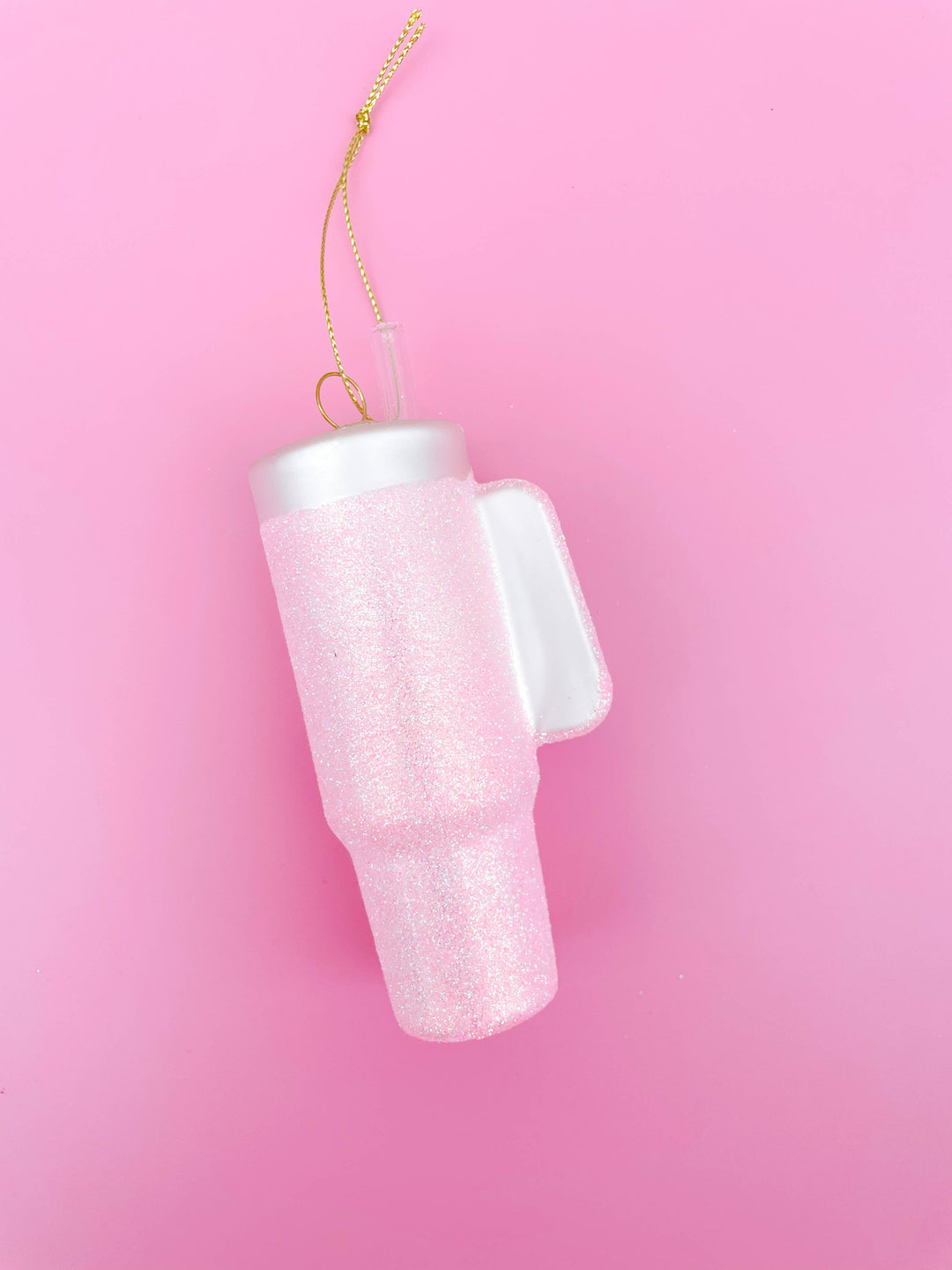 Hand-blown glass pink glittered tumbler Christmas ornament with gold hanging string.
