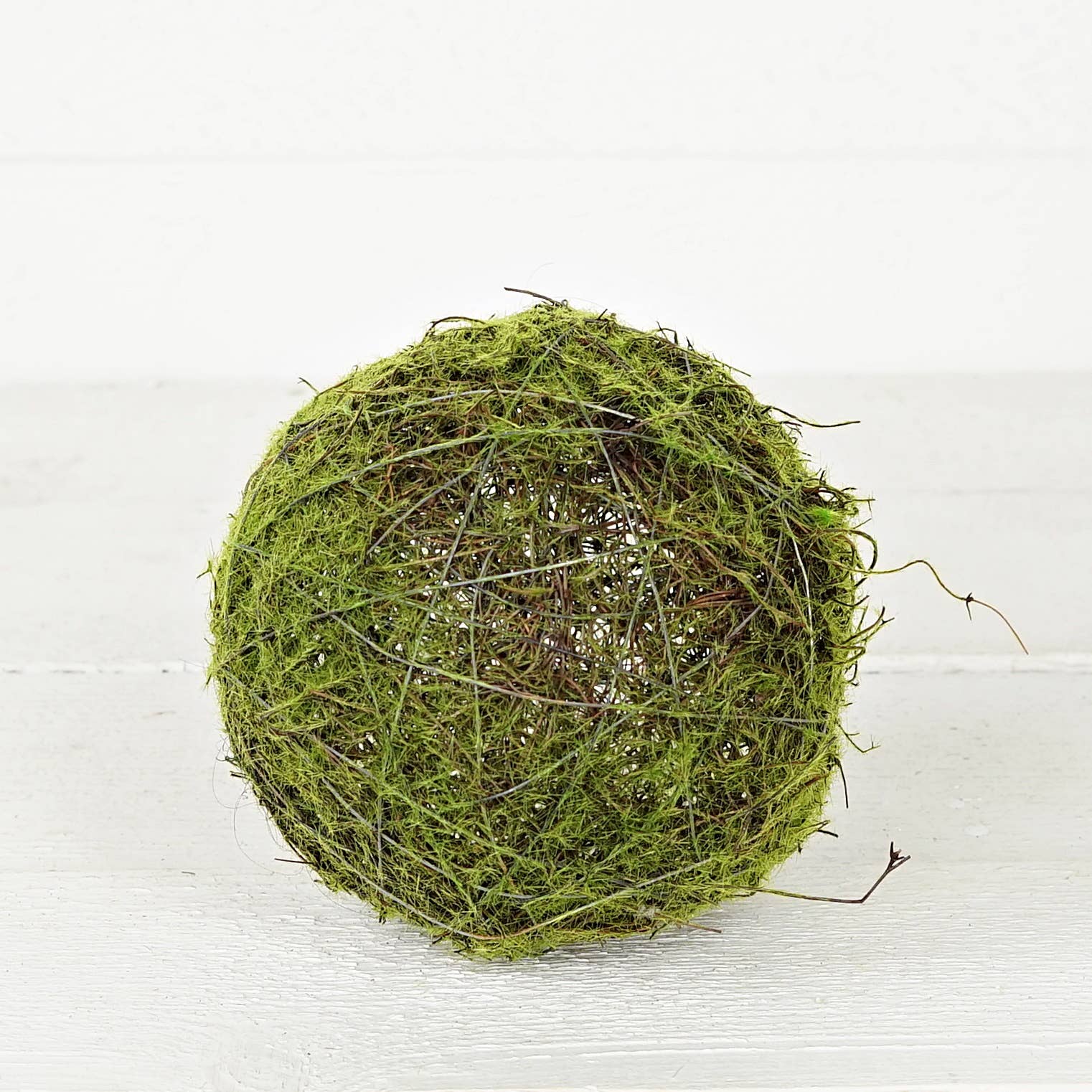 M30906- 6in Mossy Twig Ball made of green moss, thin brown twigs, and visible wire framing. Size: 6 inches.