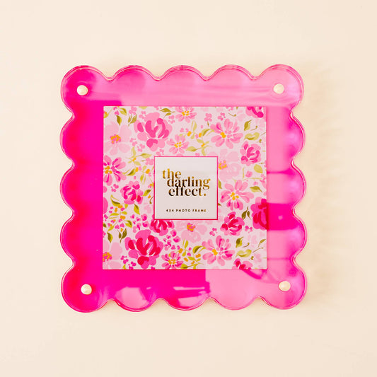 Bright pink acrylic photo frame with scalloped edges, magnetized, 4"x4" size, floral insert reads "the darling effect.