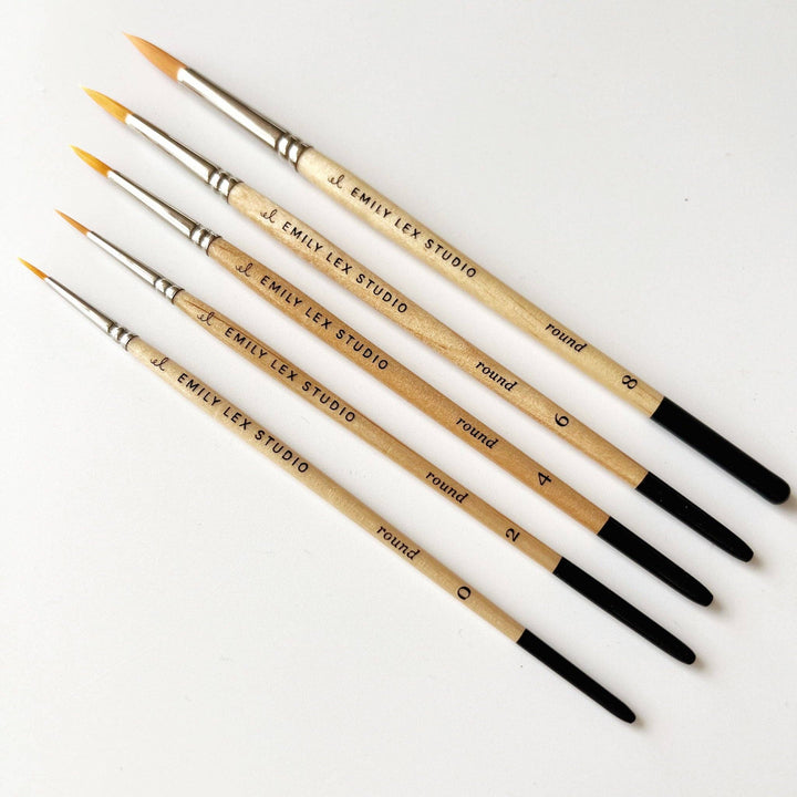 Watercolor paintbrush, size 0, natural wood handle labeled "EMILY LEX STUDIO," black tip, synthetic taklon bristles.