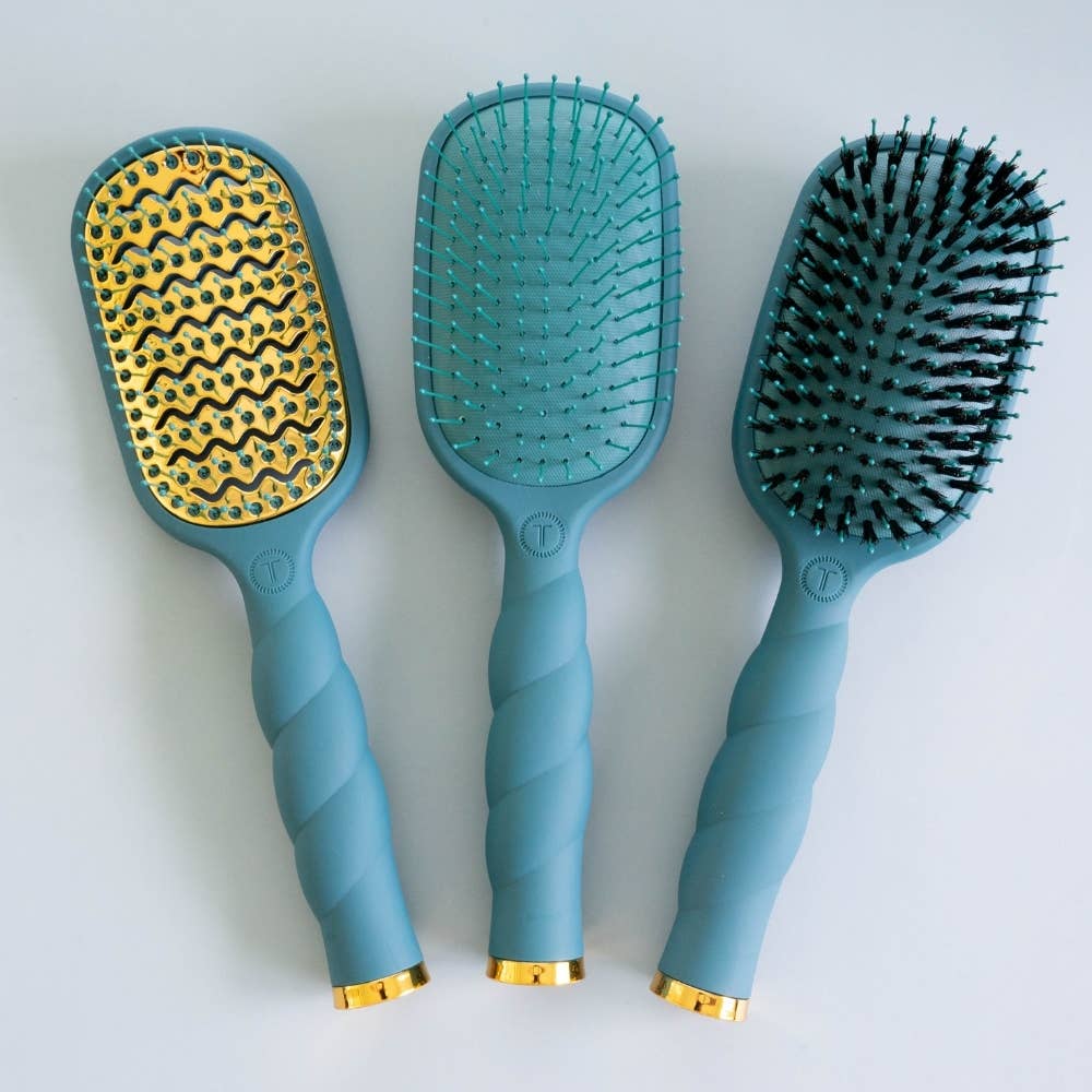 Teal “Teal With It” vented hairbrushes with gold accents, available in multiple bristle options and sizes: widely spaced plastic bristles for faster blowouts or densely packed black anti-static bristles.