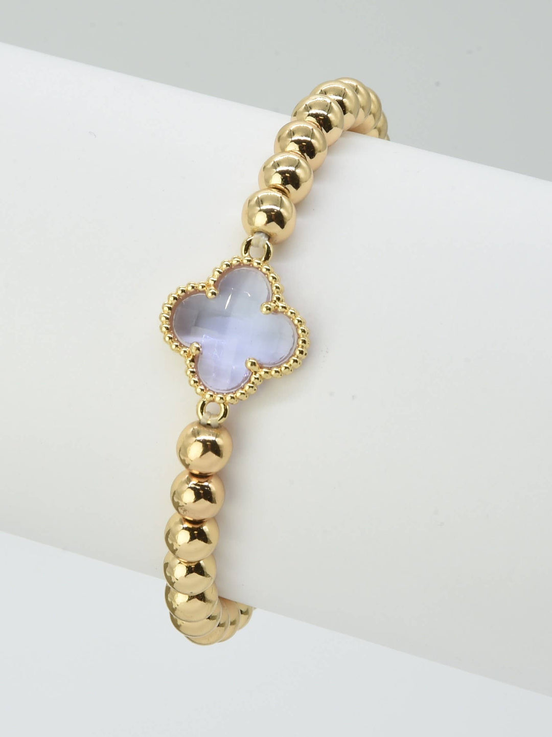 Gold beaded bracelet with a translucent pale purple crystal clover charm. Available in S, M, and L sizes.