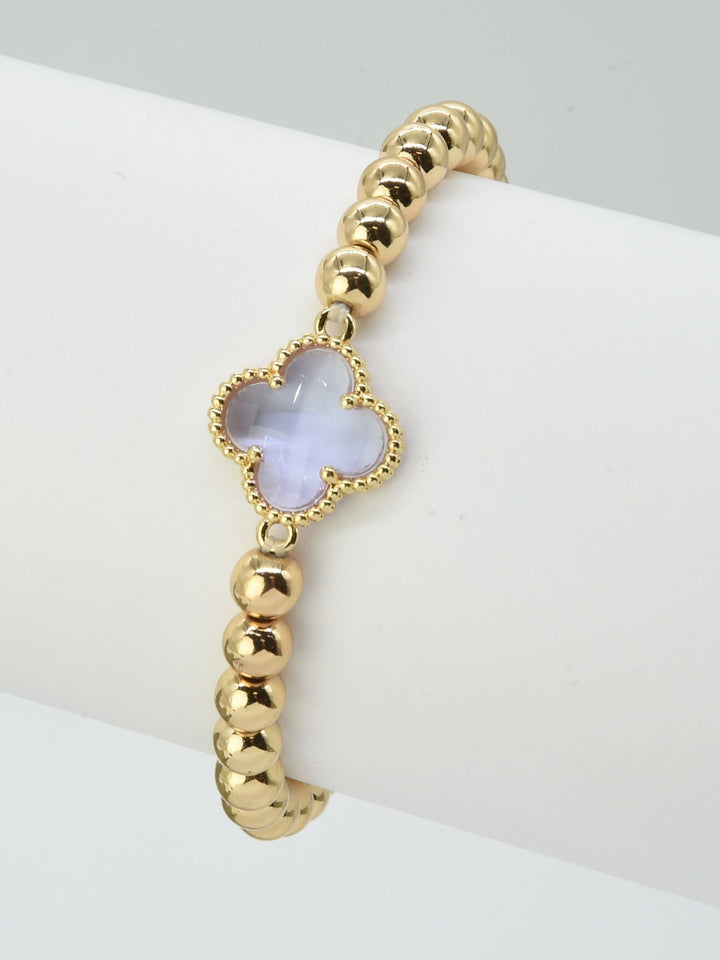Gold beaded bracelet with a translucent pale purple crystal clover charm. Available in S, M, and L sizes.