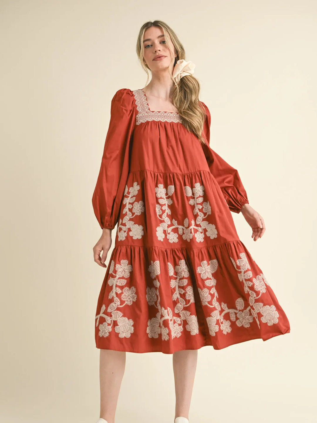Rust midi dress with long sleeves, square neckline, and cream floral embroidery. Sizes available.